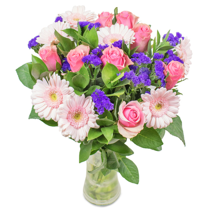 Elegantly presented in a clear glass vase, this stunning Tolworth bouquet draws together approximately seven to nine soft or medium pink roses-some still tightly closed, others unfurling with classic grace-alongside about five to seven pale pink gerbera daisies, whose cheerful, round heads and gentle centers enhance the display's vibrant fullness. Threaded through the arrangement are clusters of vivid purple statice, delivering dynamic texture and an eye-catching burst of colour that plays beautifully against the dominant pink tones. Lush, deep green foliage serves as a generous base, imparting a sense of freshness reminiscent of Tolworth's leafy avenues and neighbourhood greens. Visible stems and fresh water add a sense of natural beauty and care, marking the arrangement as ideal for local gifting-be it birthdays, Mother's Day, or cheerful tokens for office desks on Tolworth Broadway. This bouquet, crafted with local expertise, expresses joy, celebration, and a distinctive affectionate spirit perfect for the community.